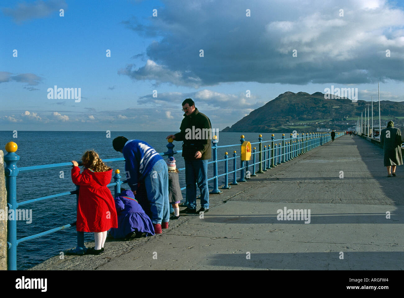 Una famiglia guardare oltre le ringhiere di Bray passeggiata a testa in giù nel mare Foto Stock
