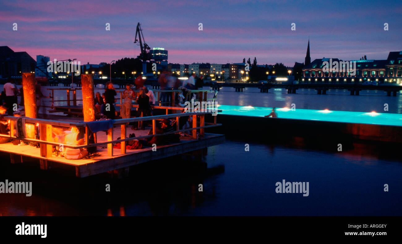 Berlino. Badeschiff an der Arena am Abend. Badeschiff in serata. La gente di nuoto, rilassarsi e godersi il tramonto e lo skyline. Foto Stock
