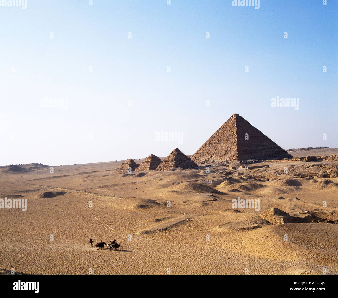 La IV dinastia complesso della piramide di Menkaure affiancato da tre piccole piramidi sussidiaria della regine nella parte anteriore più piccola delle piramidi di Giza impostato sul loro altopiano nel deserto Foto Stock