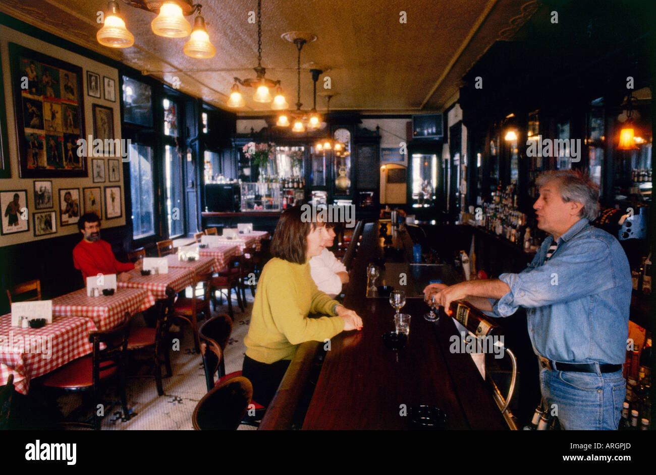 I clienti di rilassarsi al bar con un drink e chiacchierare al barista o ordinare del cibo al rosso e bianco tabelle a scacchi a Fanellis cafe Foto Stock