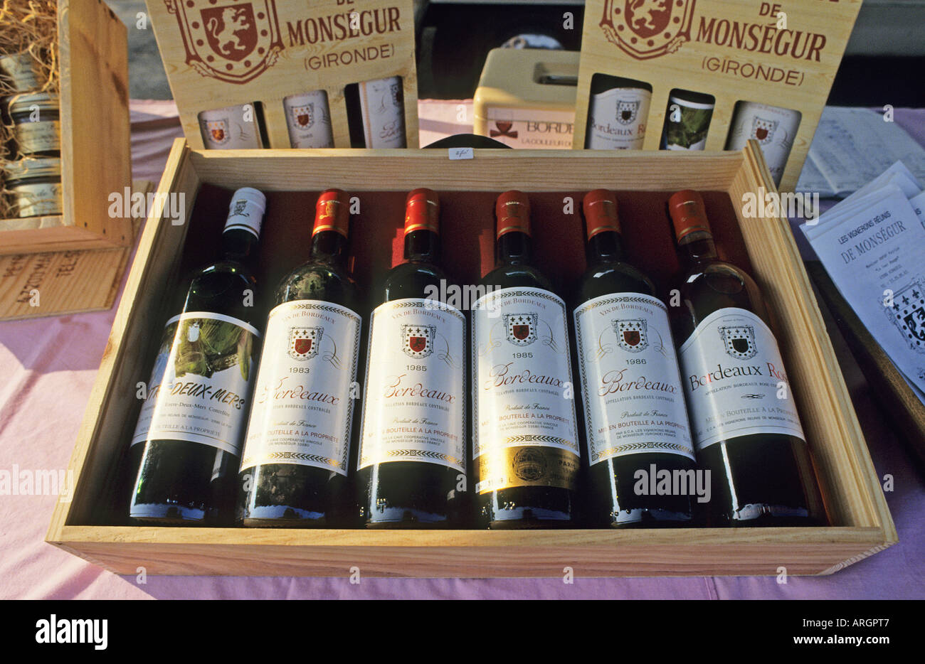 Una mezza dozzina di bottiglie di un assortimento di vini Bordeaux visualizzati in una scatola di legno su una fase di stallo nel soleggiato street market a Biscarrosse sulla Cote d Argent Foto Stock