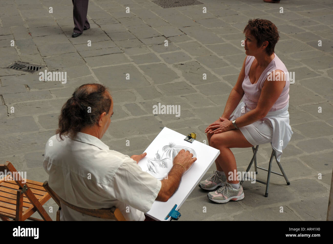 Un artista disegna una caricatura di un turista al di fuori della Galleria degli Uffizi a Firenze, Italia Foto Stock