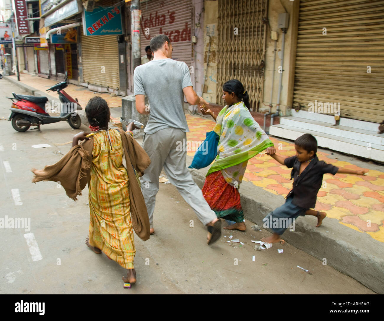 Un turista occidentale dà soldi ai bambini mendicanti in India Foto Stock