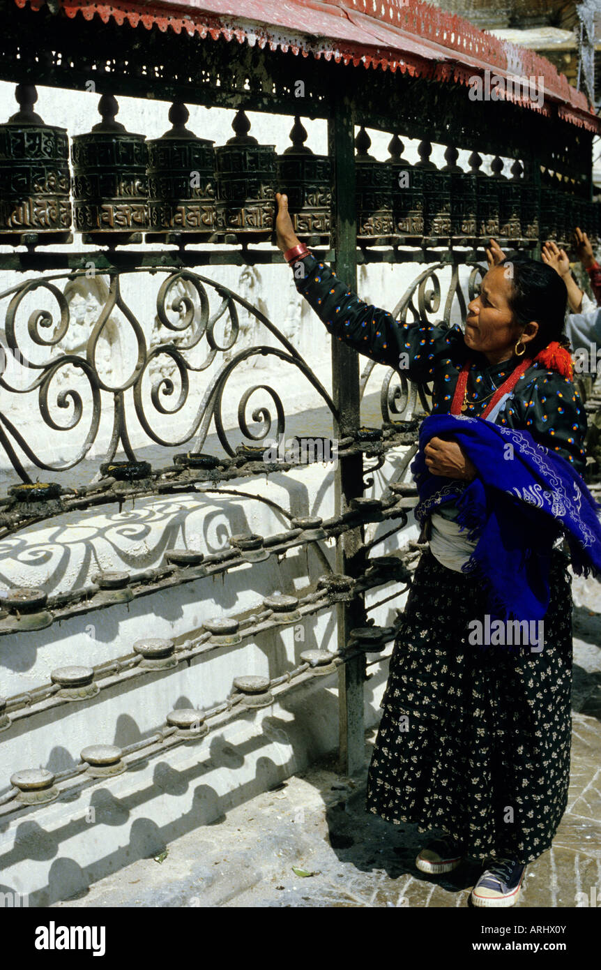 Donna che tocca una ruota di preghiera a Bodnath stupa, Nepal Foto Stock