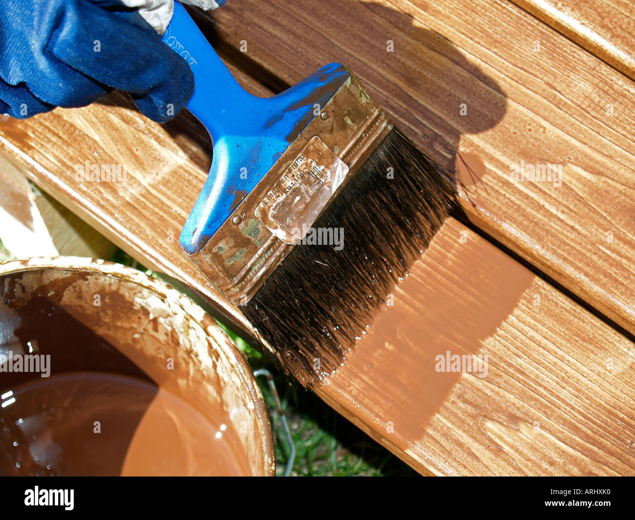 Il trattamento del legno con rivestimento protettivo di una spazzola di vernice della pittura con doghe in legno Foto Stock