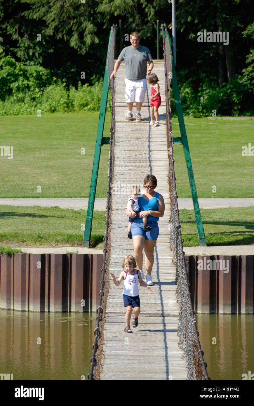 La famiglia passeggiate attraverso una sospensione oscillante ponte pedonale a Croswell Michigan Foto Stock