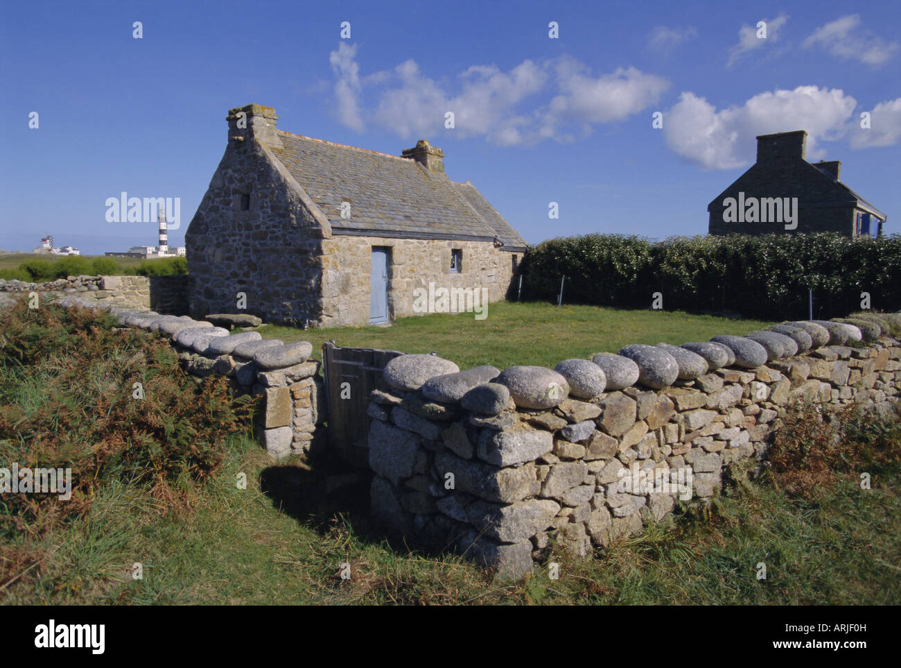 Antica casa con Creac'h faro dietro sulla isola di Ouessant, Bretagna, Francia, Europa Foto Stock