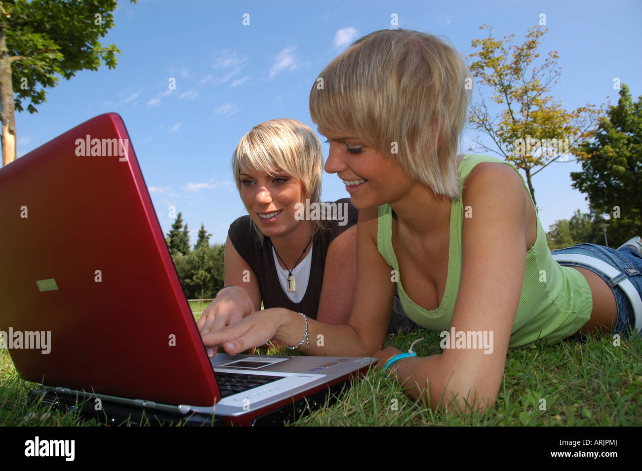 Junge Mädchen mit laptop giovani auf wiese - ragazze giacente in erba lavora con i notebook Foto Stock