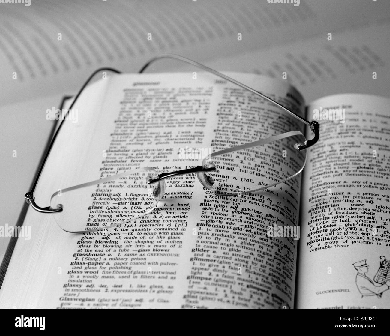 Paio di Occhiali giacente su un libro aperto evidenziando la parola occhiali, occhiali attraverso uno della lente Foto Stock