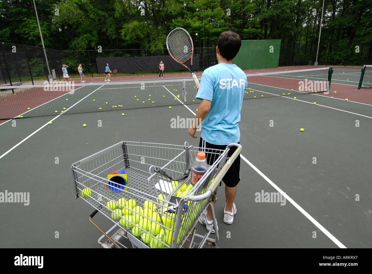 Pubblico Teen maestro di tennis corre un estate clinica di apprendimento Foto Stock