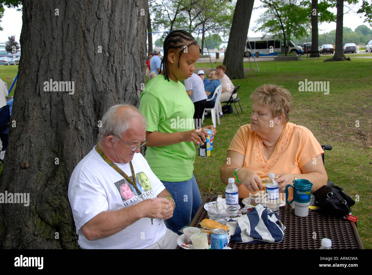 Scuola superiore di età compresa tra i ragazzi aiutano a servire i cittadini anziani ad un picnic in un parco pubblico Foto Stock
