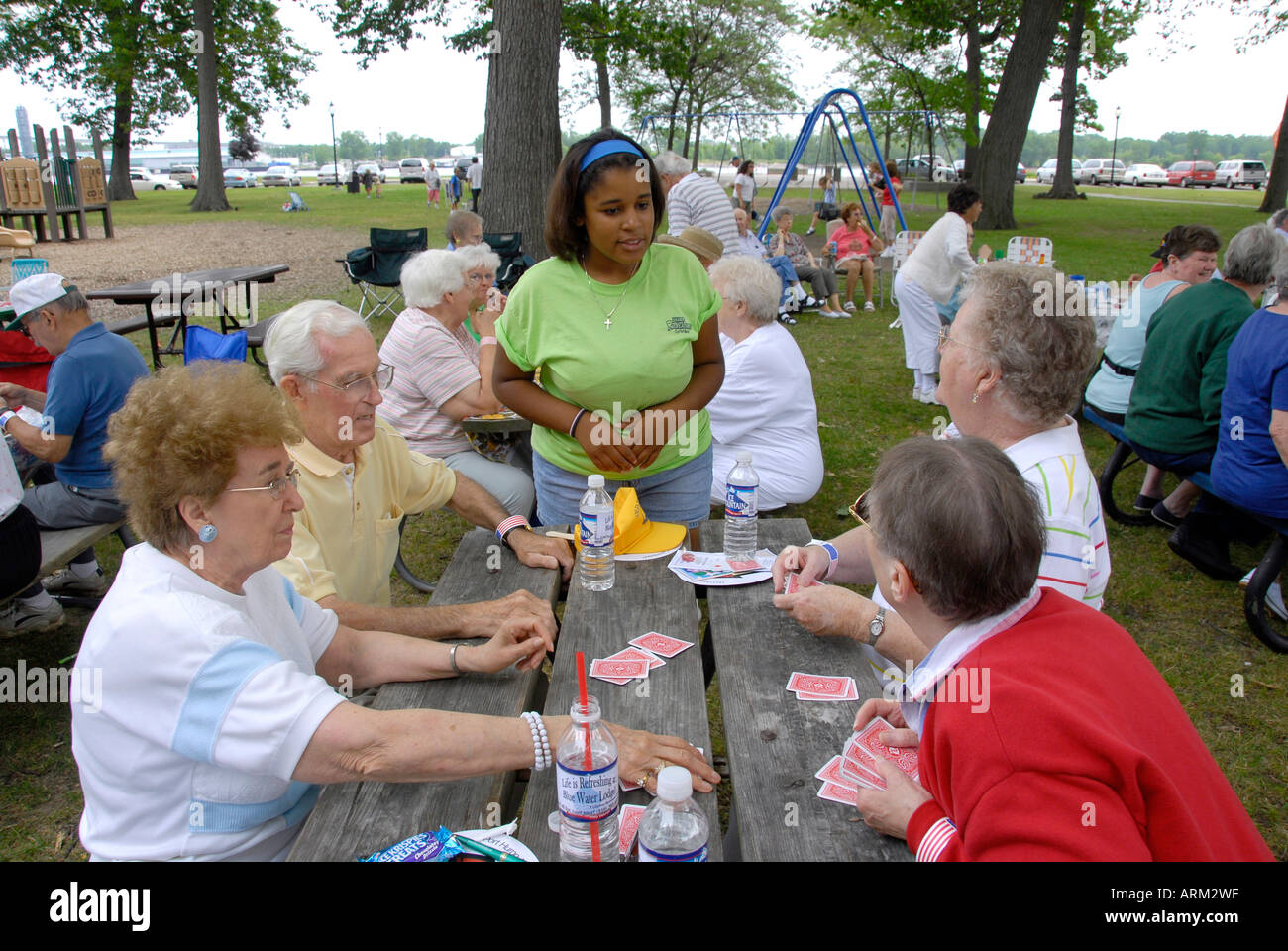 Scuola superiore di età compresa tra i ragazzi aiutano a servire i cittadini anziani ad un picnic in un parco pubblico Foto Stock