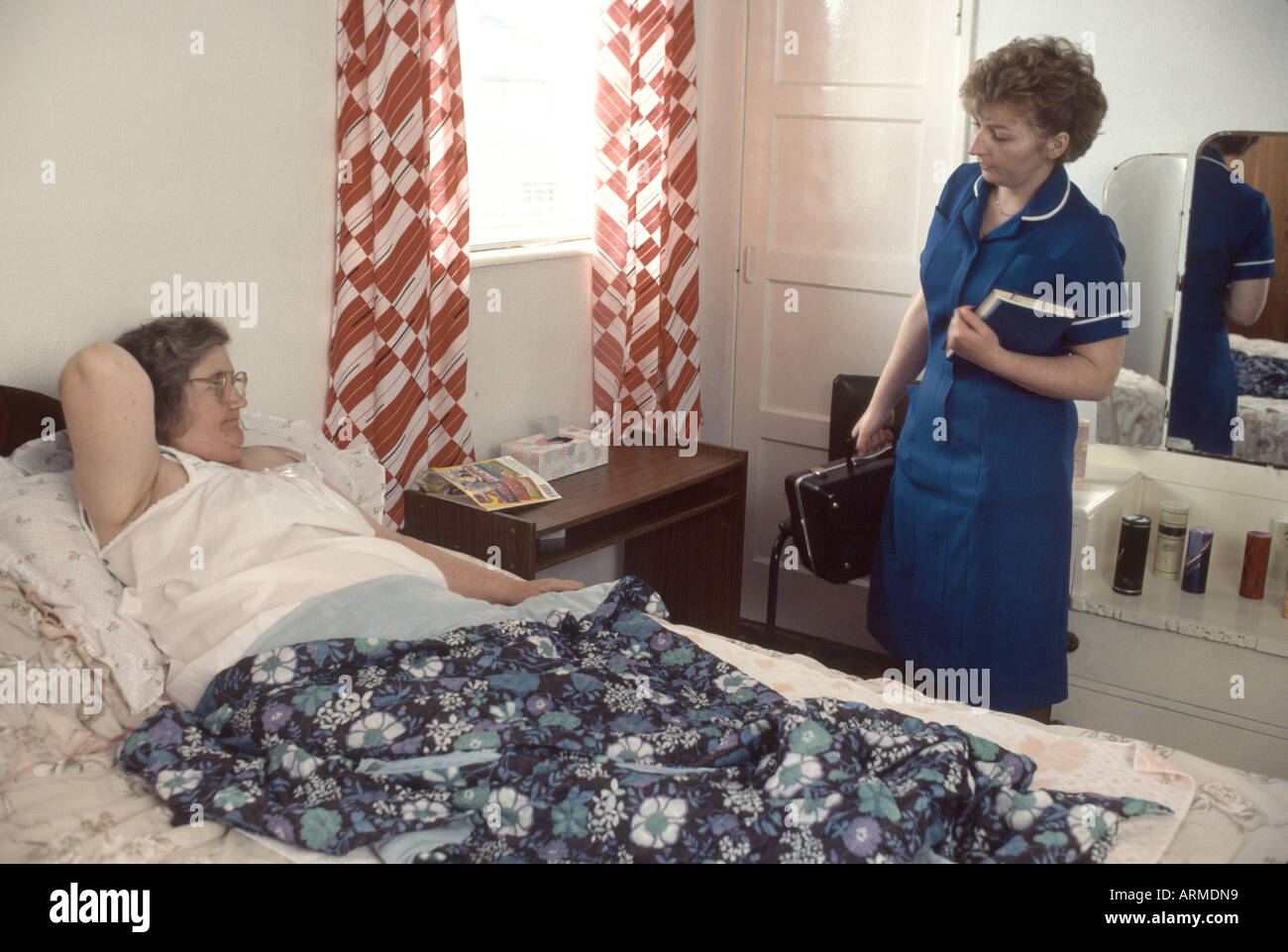 District nurse tendente a letto cavalcato la donna nella sua casa Foto Stock