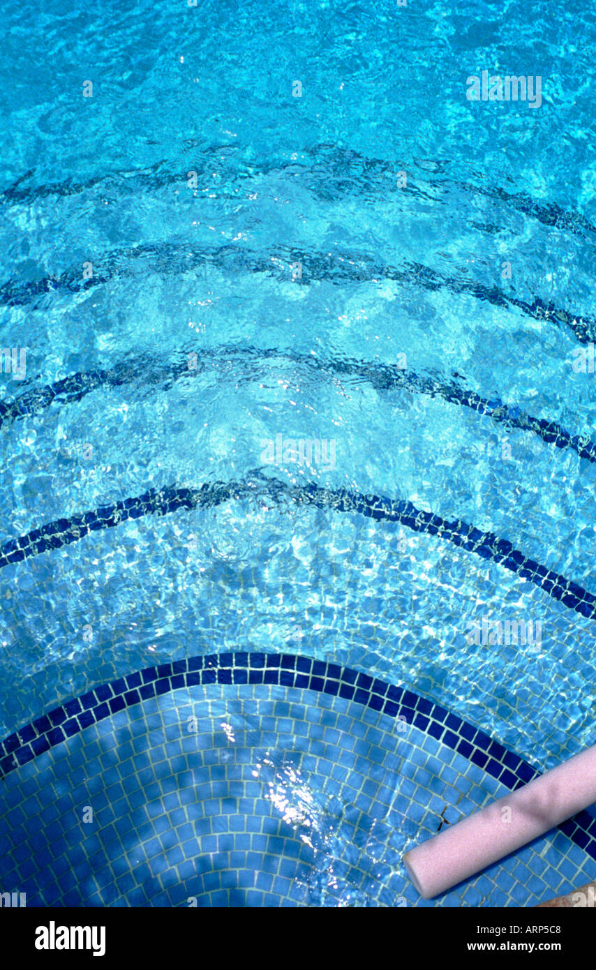 Riassunto della piscina con piastrelle blu scuro che segnano il bordo dei gradini e la luce solare che gioca sulla superficie di acqua blu brillante. La Manga, Murcia, Spagna. Foto Stock