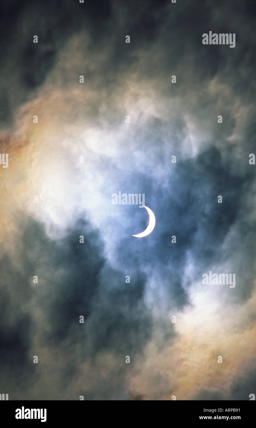 Eclissi solare. Luna passa davanti al sole quasi pieno di eclipse. Atmosfera romantica velata da sottili tempestoso cloud di compensazione Foto Stock