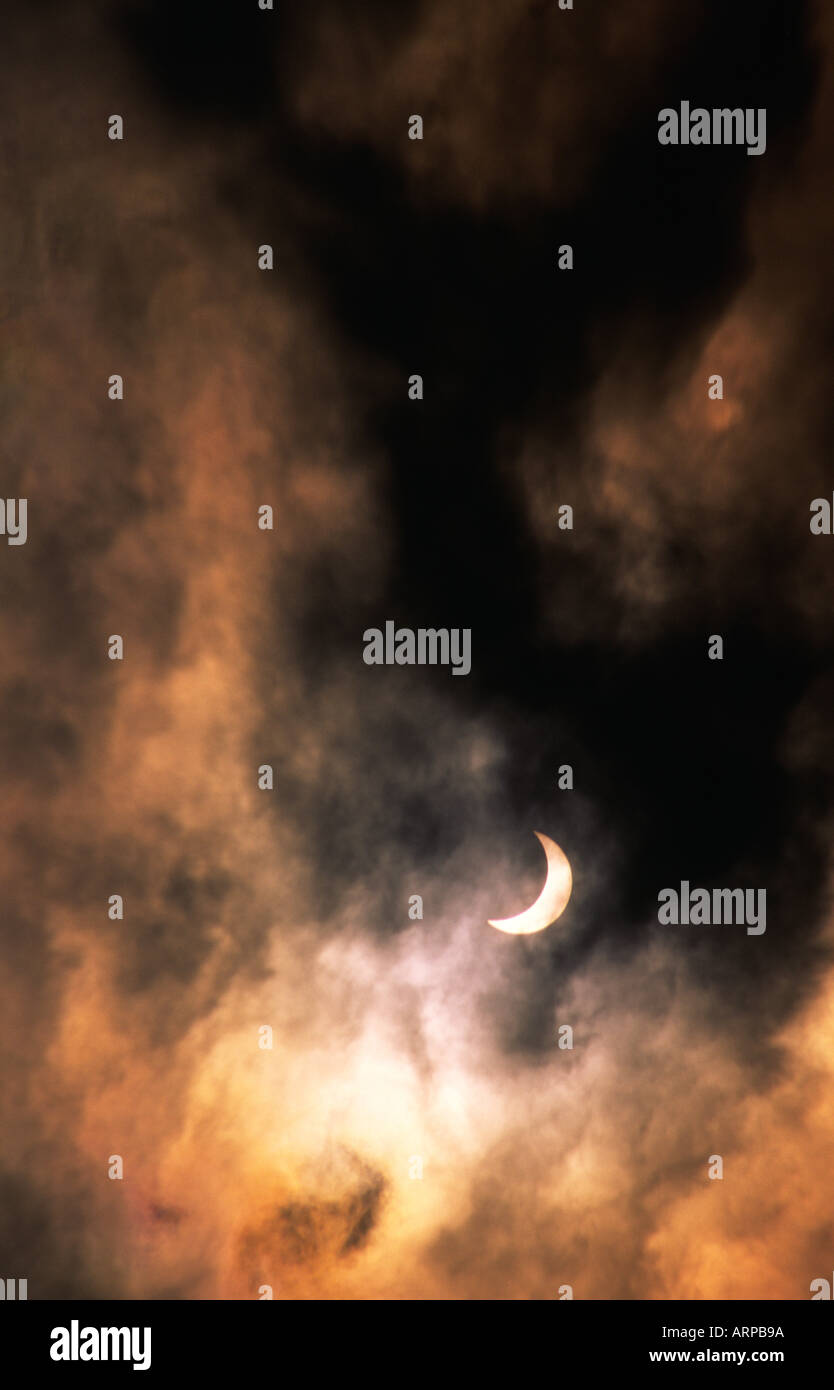 Eclissi solare. Luna passa davanti al sole quasi pieno di eclipse. Atmosfera romantica velata da sottili tempestoso cloud di compensazione Foto Stock