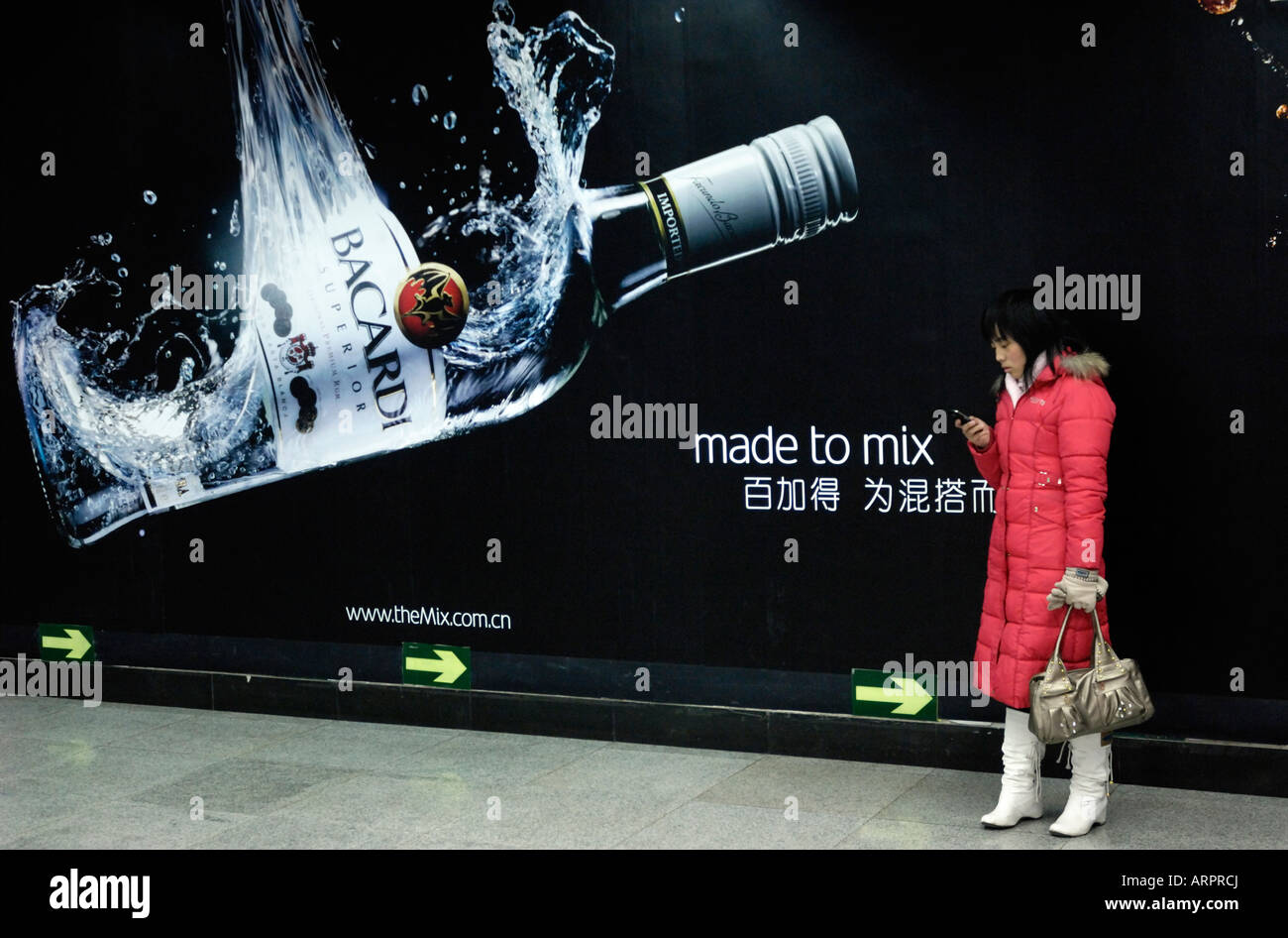 Una signora controlla il suo cellulare nella parte anteriore del Bacardi affissioni a Pechino in Cina.15-Feb-2008 Foto Stock