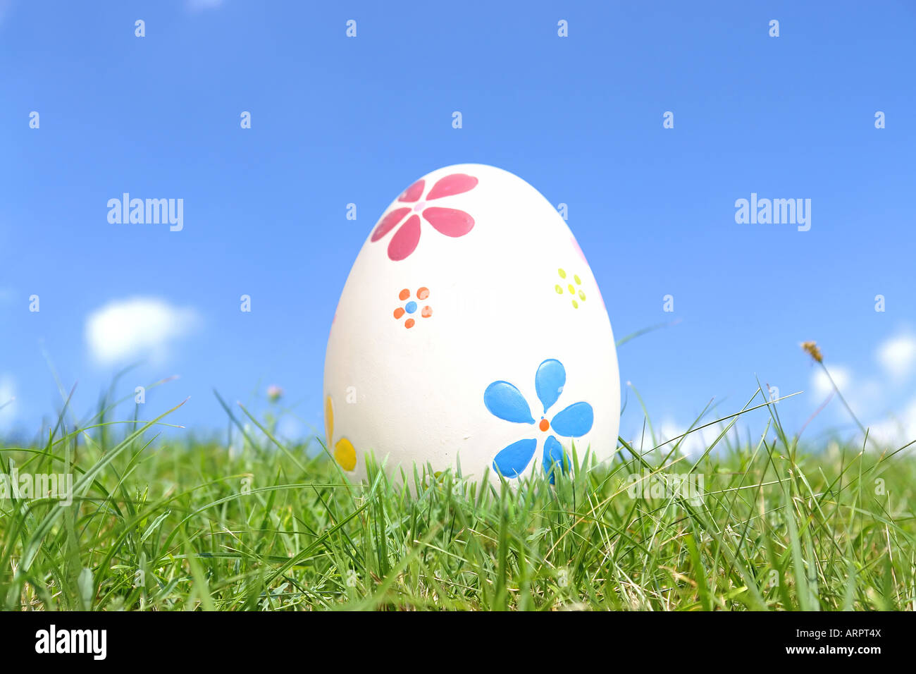 Dipinto di uovo di pasqua in erba oltre il cielo blu Foto Stock