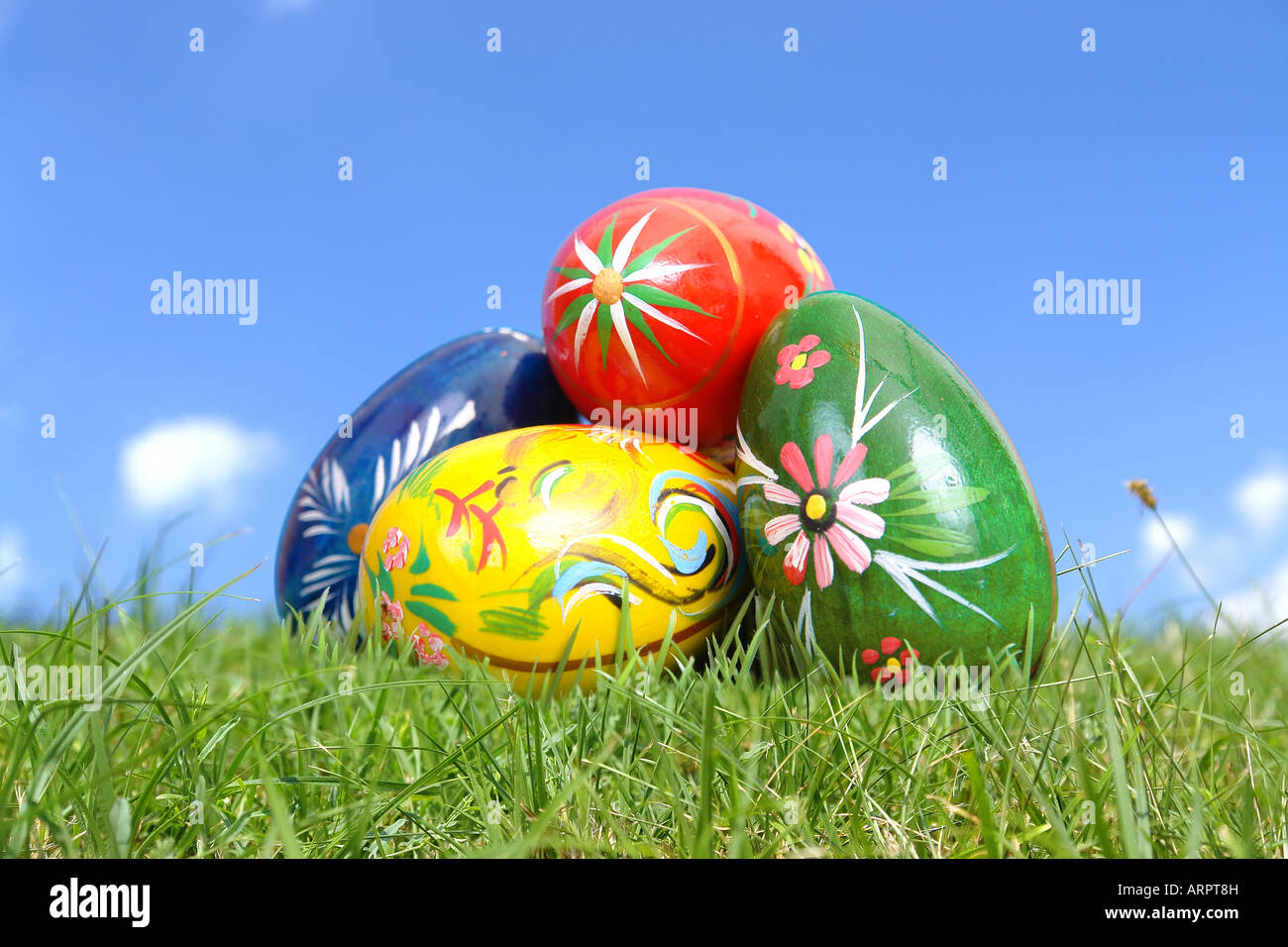 Cumulo di dipinto di uova di pasqua in posa in erba oltre il cielo blu Foto Stock