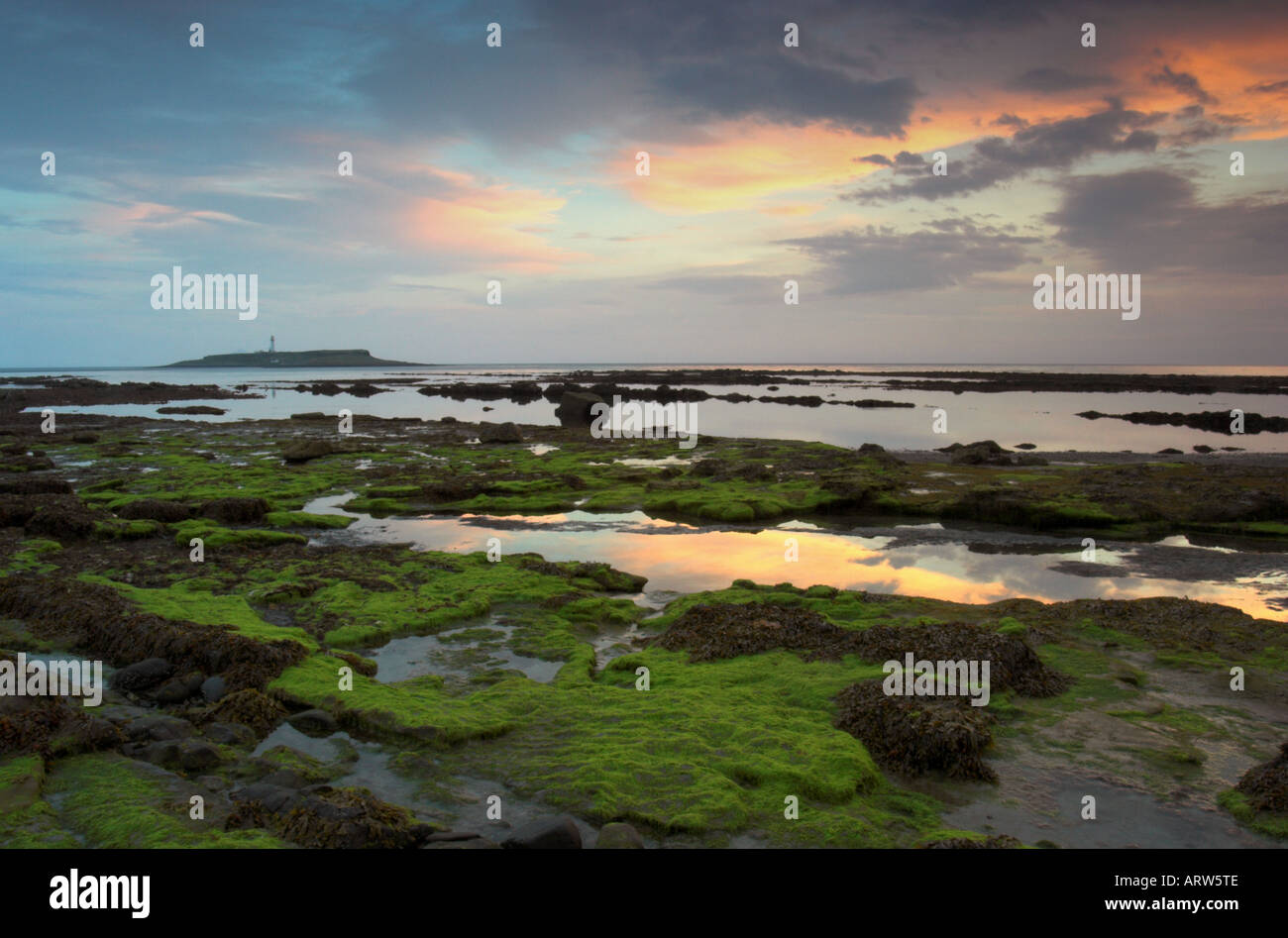 Foto paesaggio del litorale di Kildonan sull'isola di Arran al tramonto con Pladda island e il faro in background Foto Stock