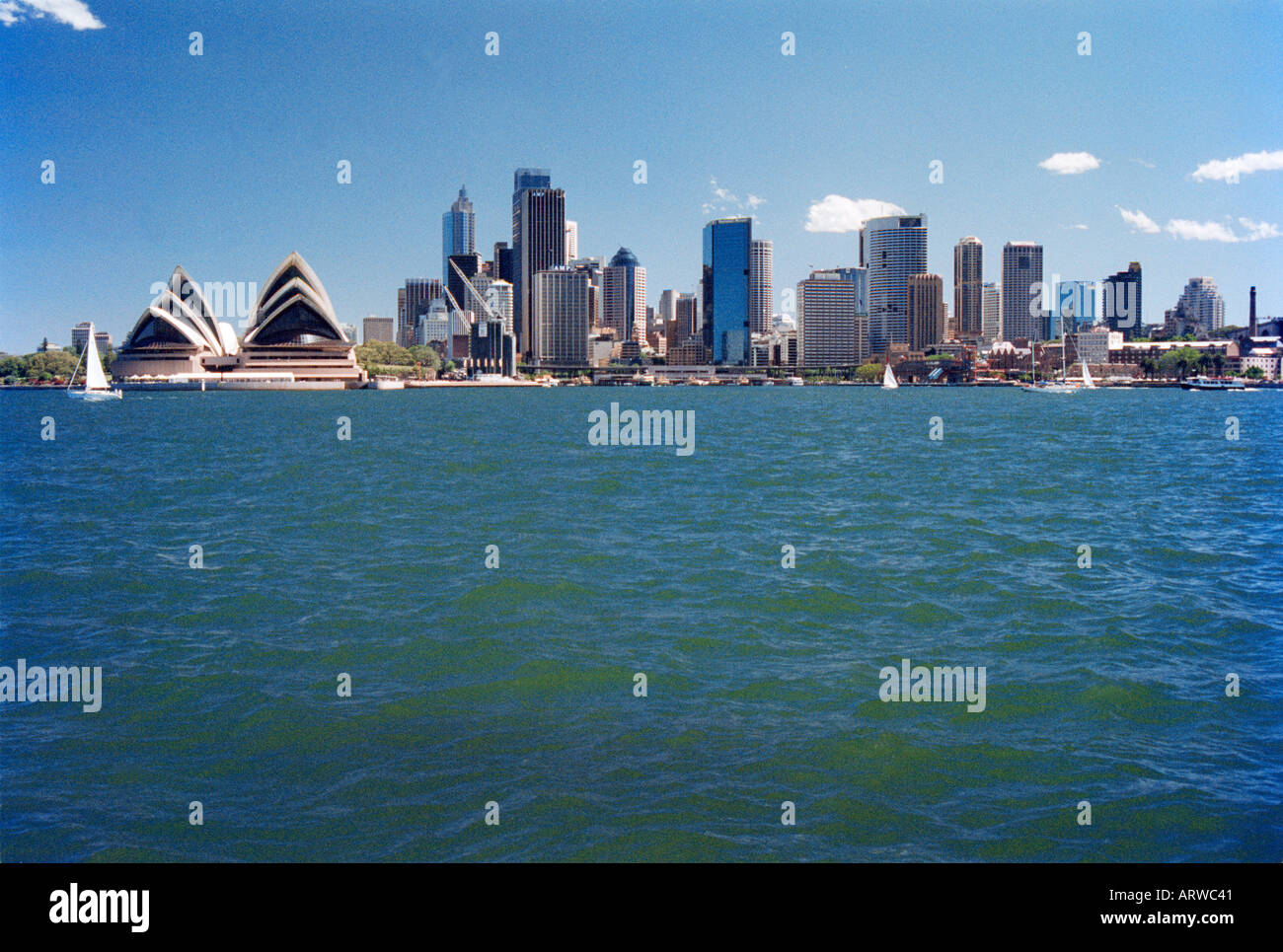 La Opera House di Sydney e il quartiere centrale degli affari visto da attraverso il porto Foto Stock