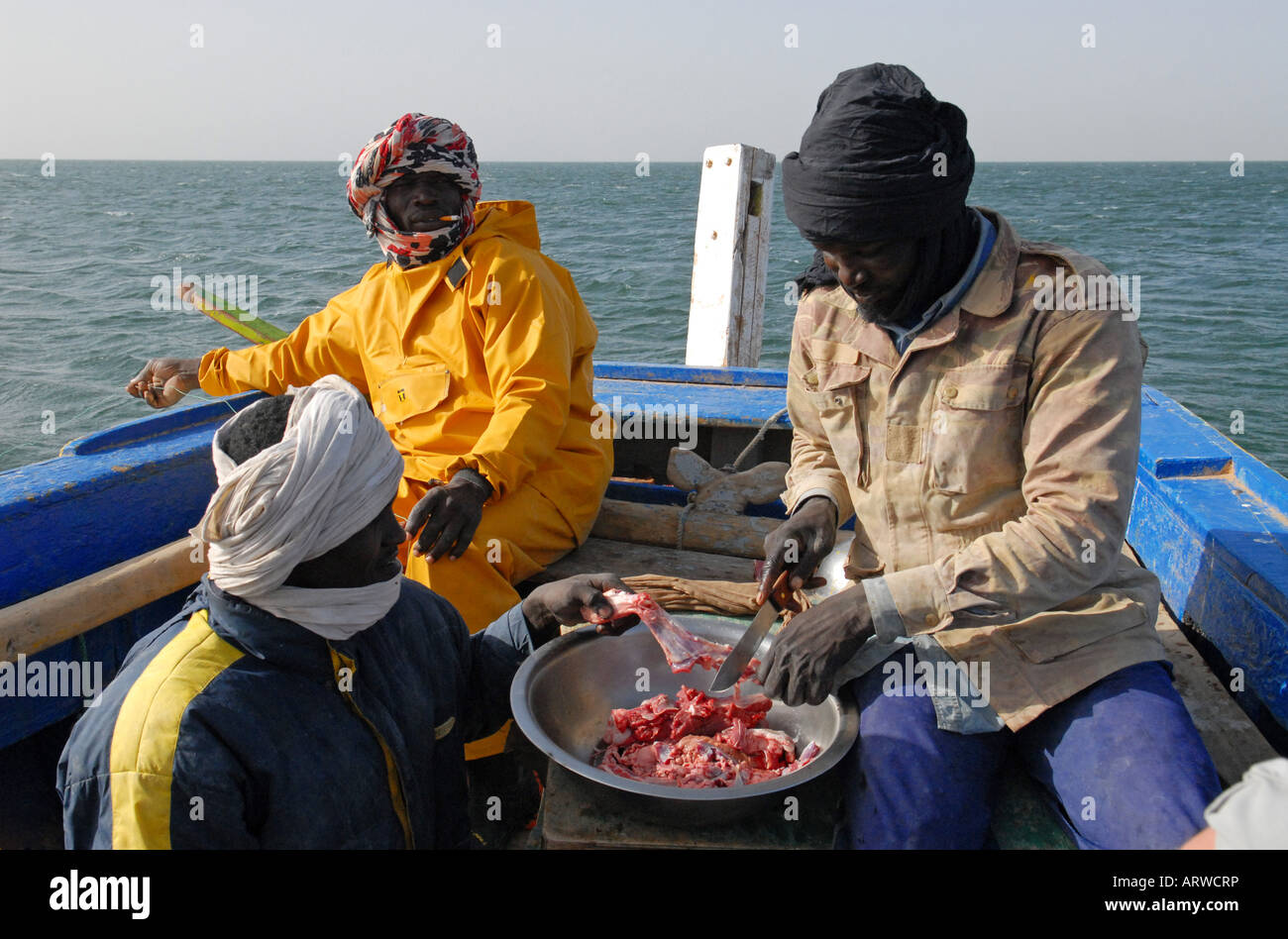 I pescatori la cottura della carne sulla loro barca Mauritania Foto Stock