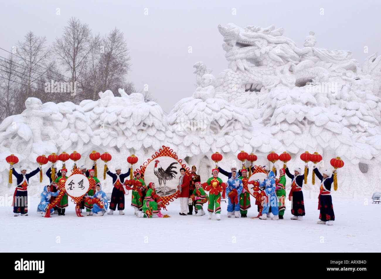 Un gruppo in abito nazionale pone di fronte a una grande scultura di neve ad accogliere l Anno del Gallo a Harbin Cina 2005 Foto Stock