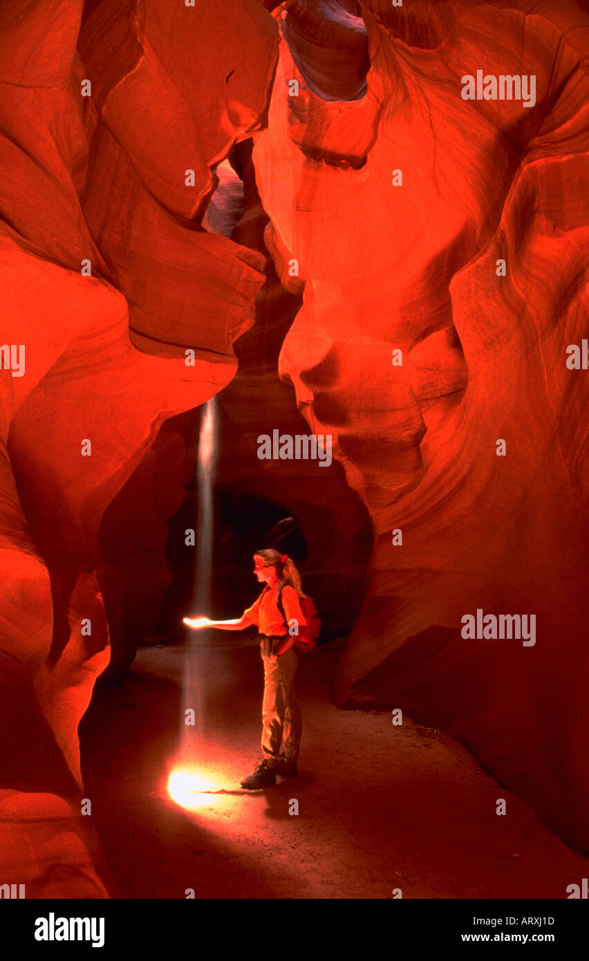 Donna che mantiene la sua mano per catturare i raggi di luce shinging all'Antelope Canyon Foto Stock