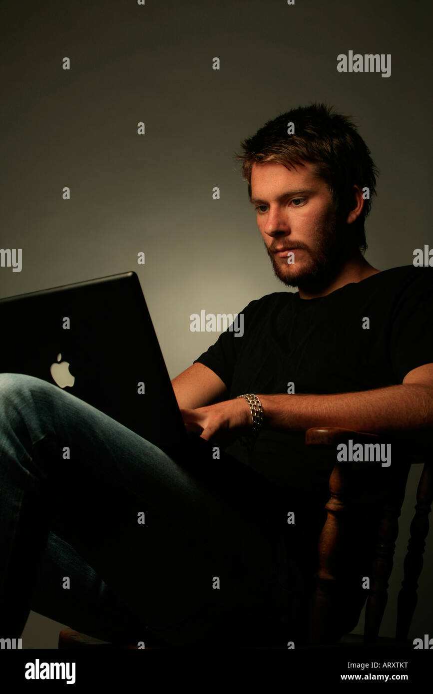 Moda giovane uomo in jeans con il computer Foto Stock