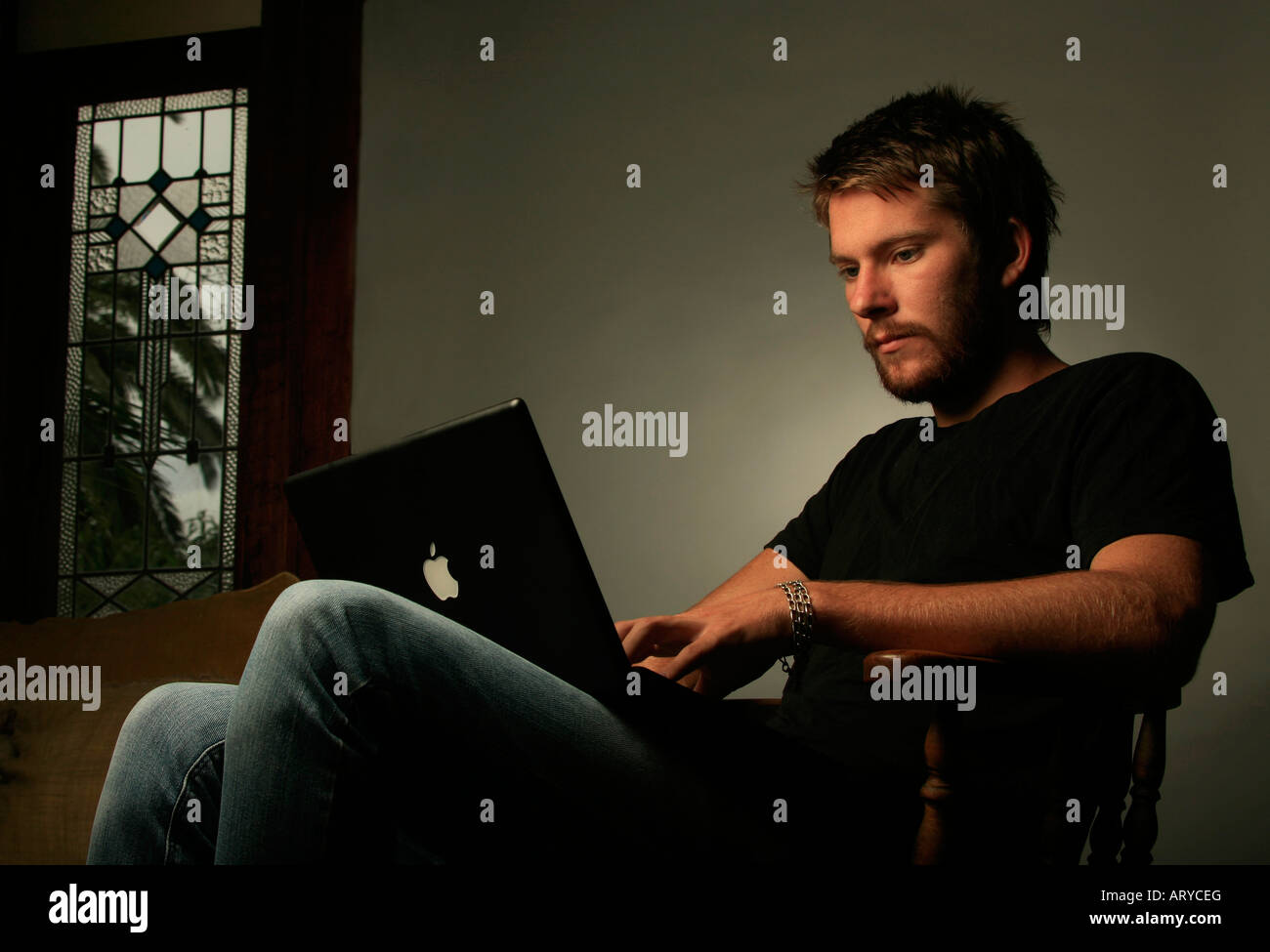 Moda giovane uomo in jeans con il computer Foto Stock