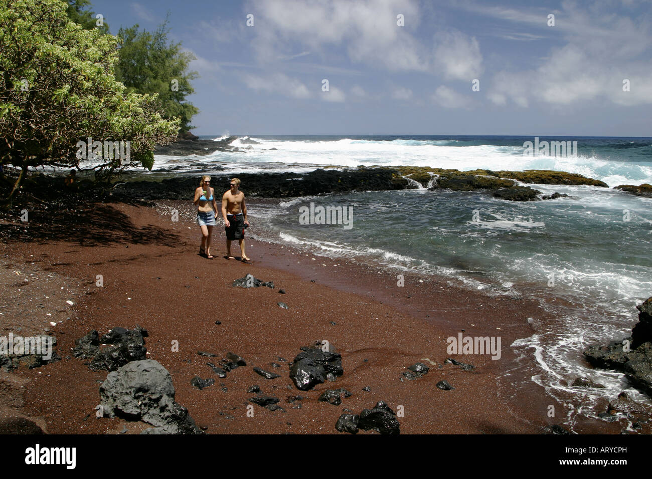 Giovane gode appartato lungomare a piedi su invitante & unique la spiaggia di sabbia rossa Kaihalulu baia ad appena pochi passi di distanza dalla città di Hana Foto Stock
