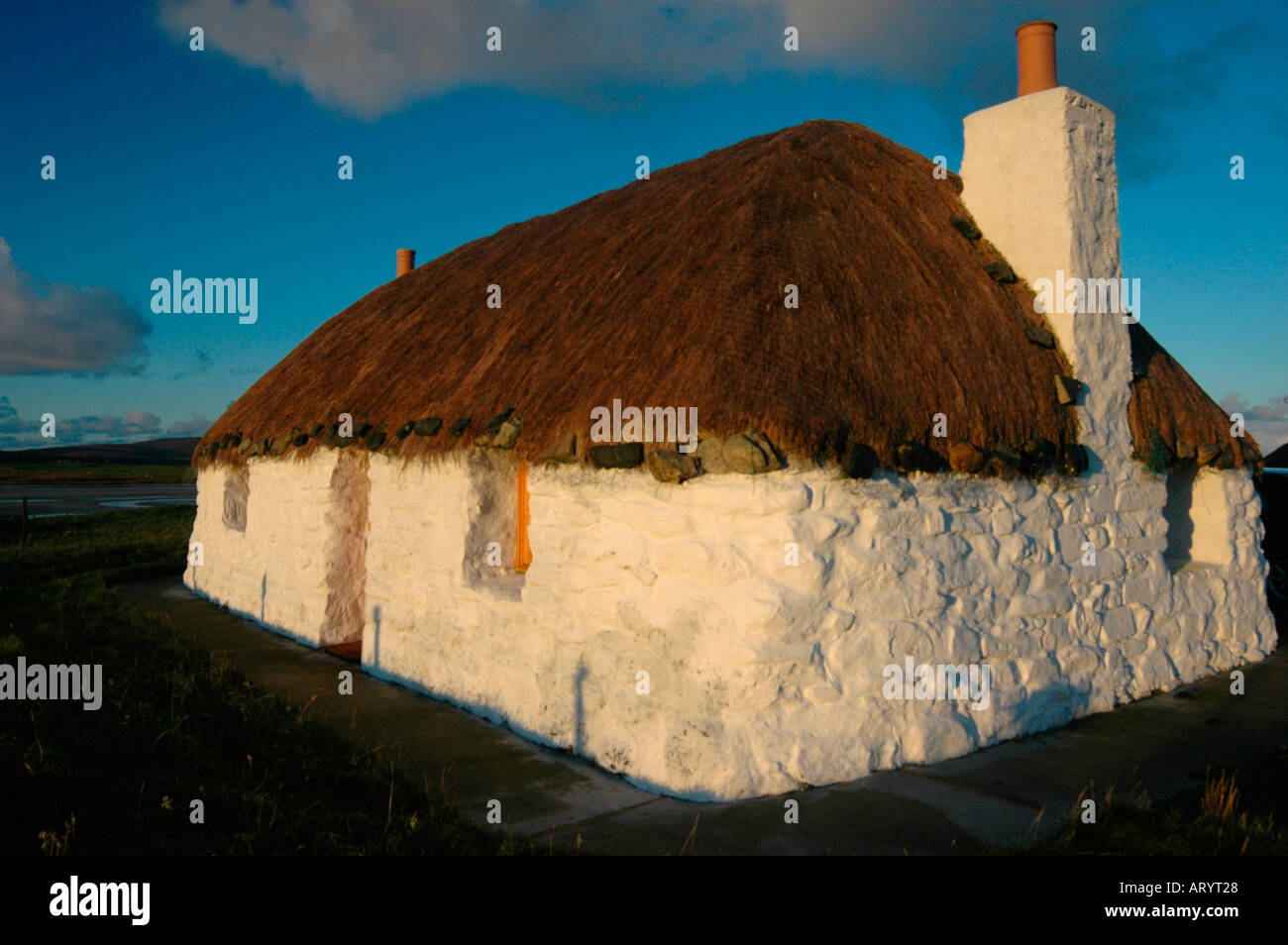 Un tradizionale dipinto di bianco con tetto di paglia di casa di pietra Foto Stock
