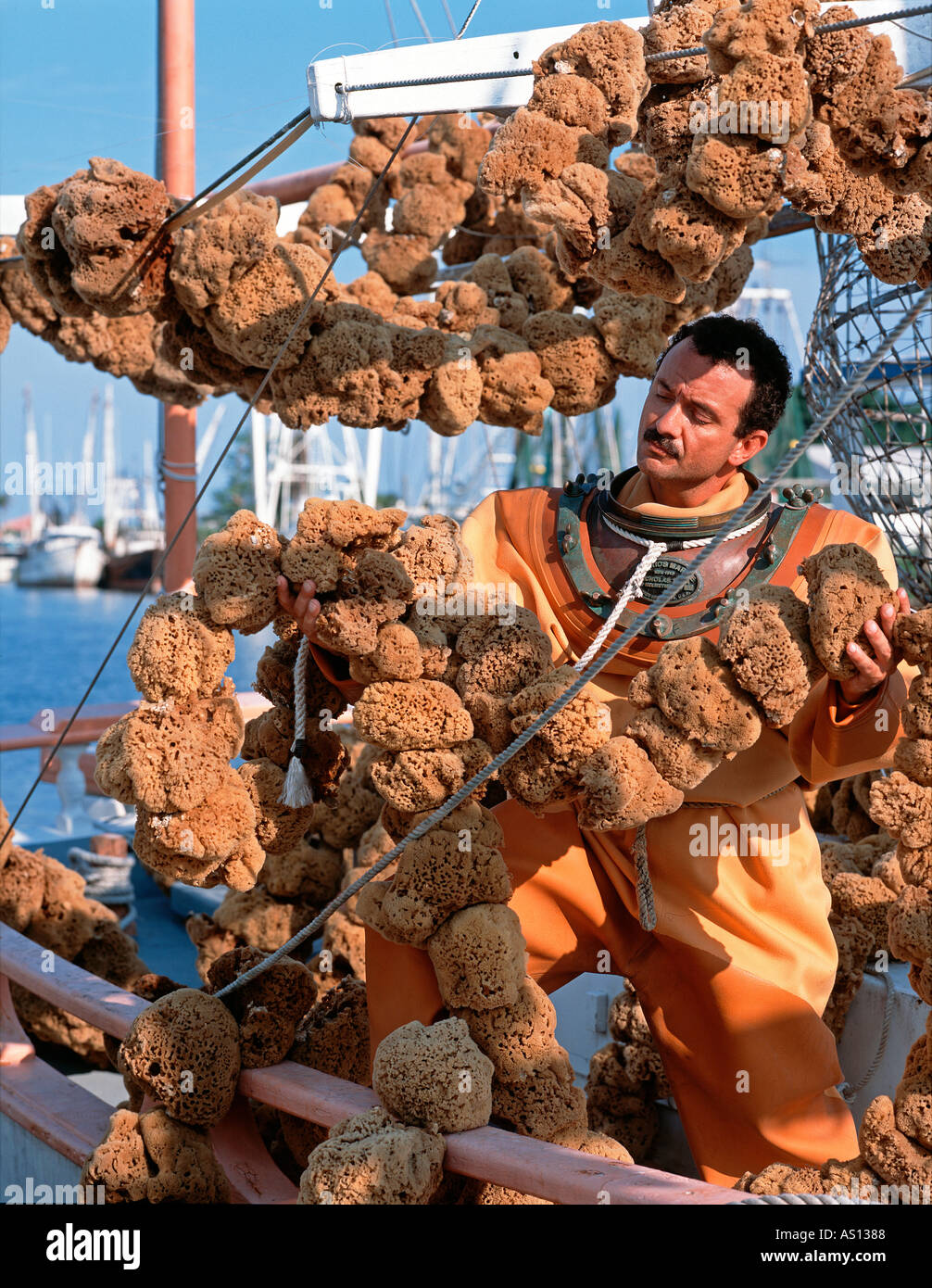 Spugna subacqueo in arancione skafandro muta guardando spugne sulla sua barca in Tarpon Springs Florida Foto Stock