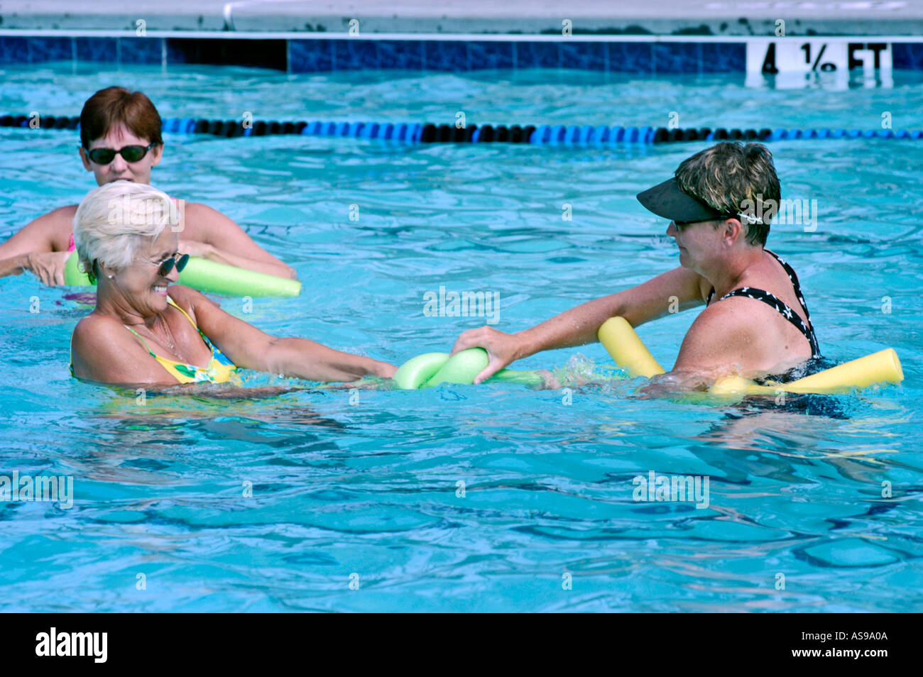 Le donne anziane in Country Club Piscina la legatura di nodi in pasta per classe di esercizio Foto Stock