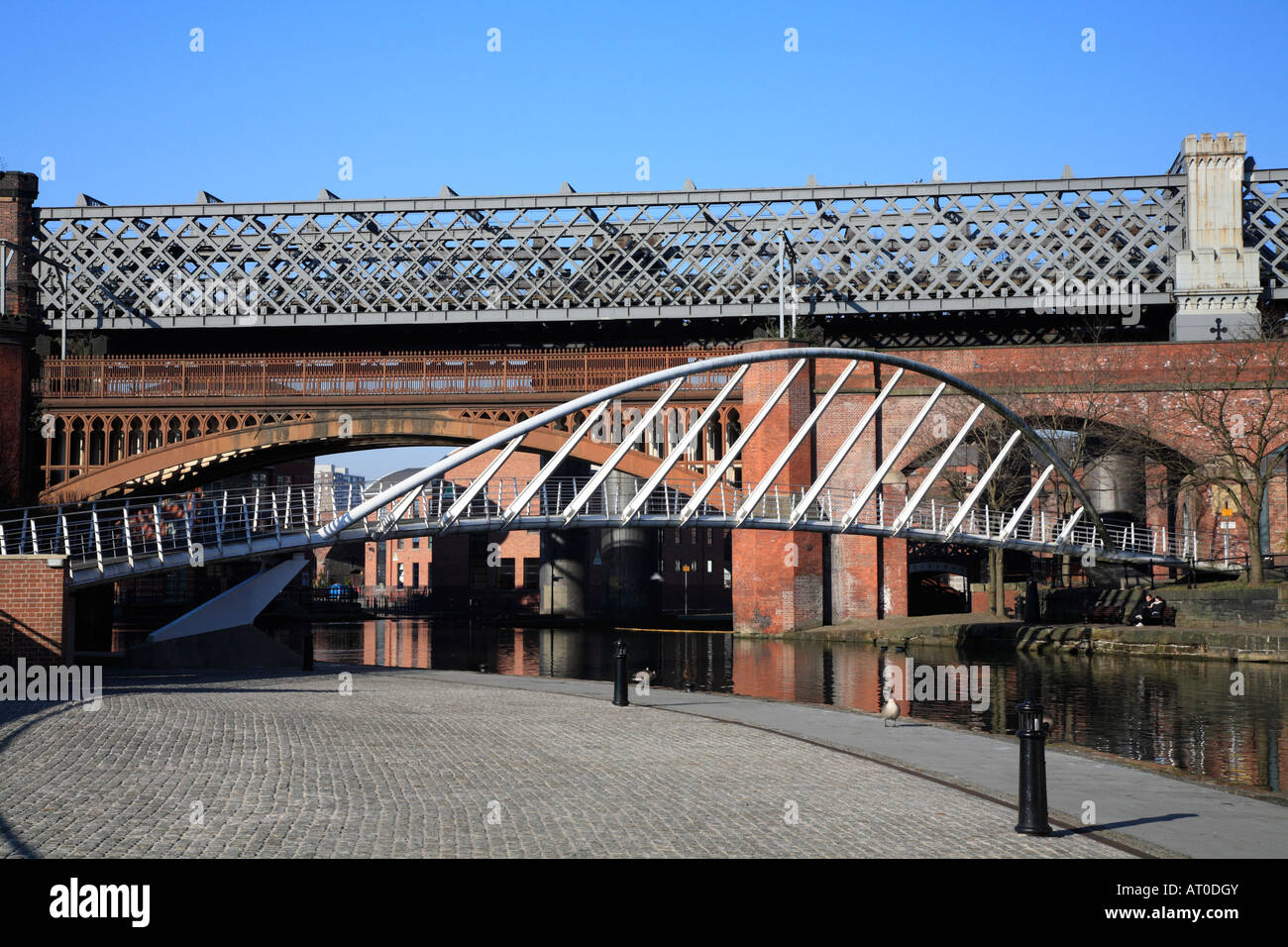 Piedino in acciaio ponte e i ponti ferroviari che attraversano la Bridgewater Canal, Castlefield, Manchester, Inghilterra, Regno Unito Foto Stock