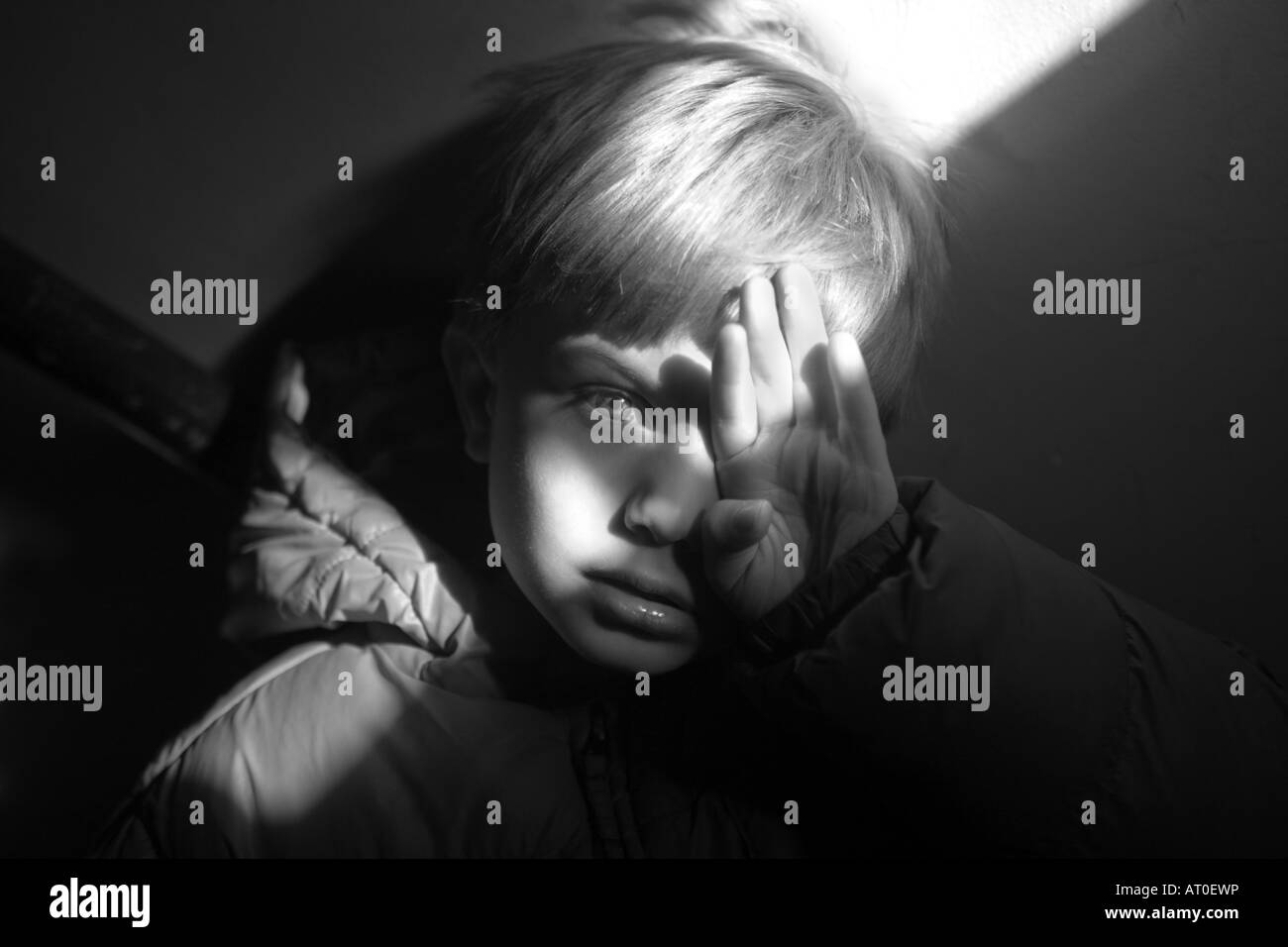 Ragazzo che guarda triste in bianco e nero con luce drammatica Foto Stock