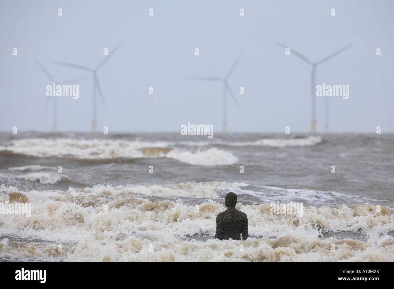 Antony Gormley scultura di uomo che guarda al mare verso il potere di vento turbine Crosby Beach Merseyside England Regno Unito GB Foto Stock