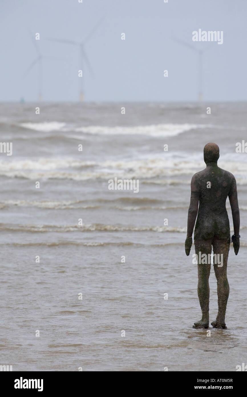 Antony Gormley scultura di uomo che guarda al mare verso il potere di vento turbine Crosby Beach Merseyside England Regno Unito GB Foto Stock