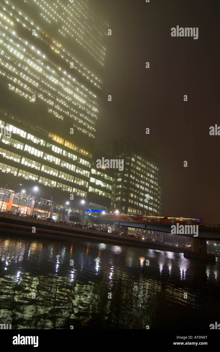 Verticale ampia angolazione di una Docklands Light Railway stazione DLR lasciando Heron Quays dalla stazione di Canary Wharf in una nebbiosa inverni di notte Foto Stock