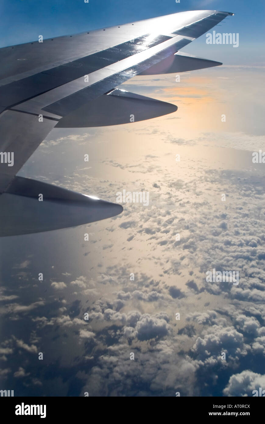 Verticale ampia angolazione del sole che tramonta e nuvole riflettono sul mare dall'interno di un aereo Foto Stock