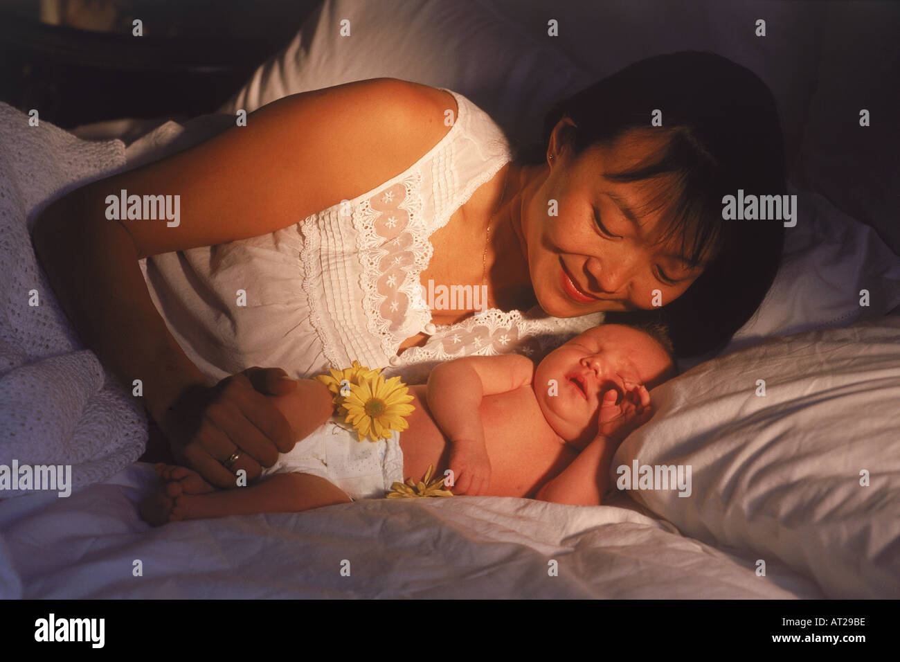 Asian madre con il suo neonato in camera da letto. La luce del mattino Foto Stock