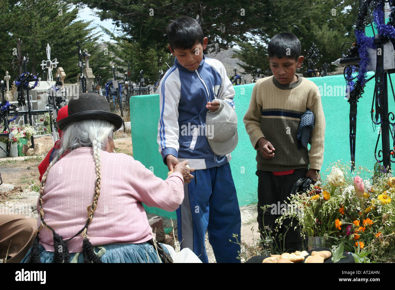 Una vecchia donna out invece il pane ai bambini venuti al cimitero per pregare per i defunti nell'altipiano della Bolivia Foto Stock