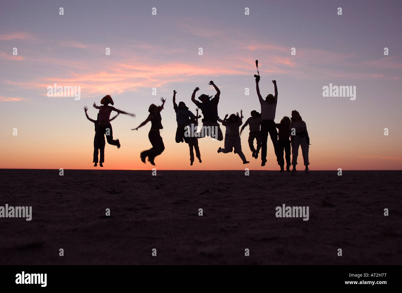 Gruppo di persone che saltano al tramonto sulla coppa di sale nel Kalahari Botswana Sud Africa Foto Stock