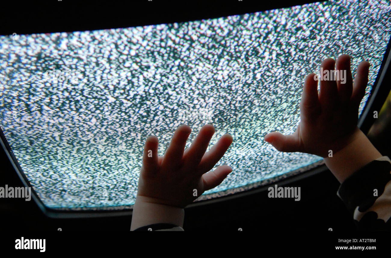 Un bambino con le mani in mano toccare un televisore statico Foto Stock