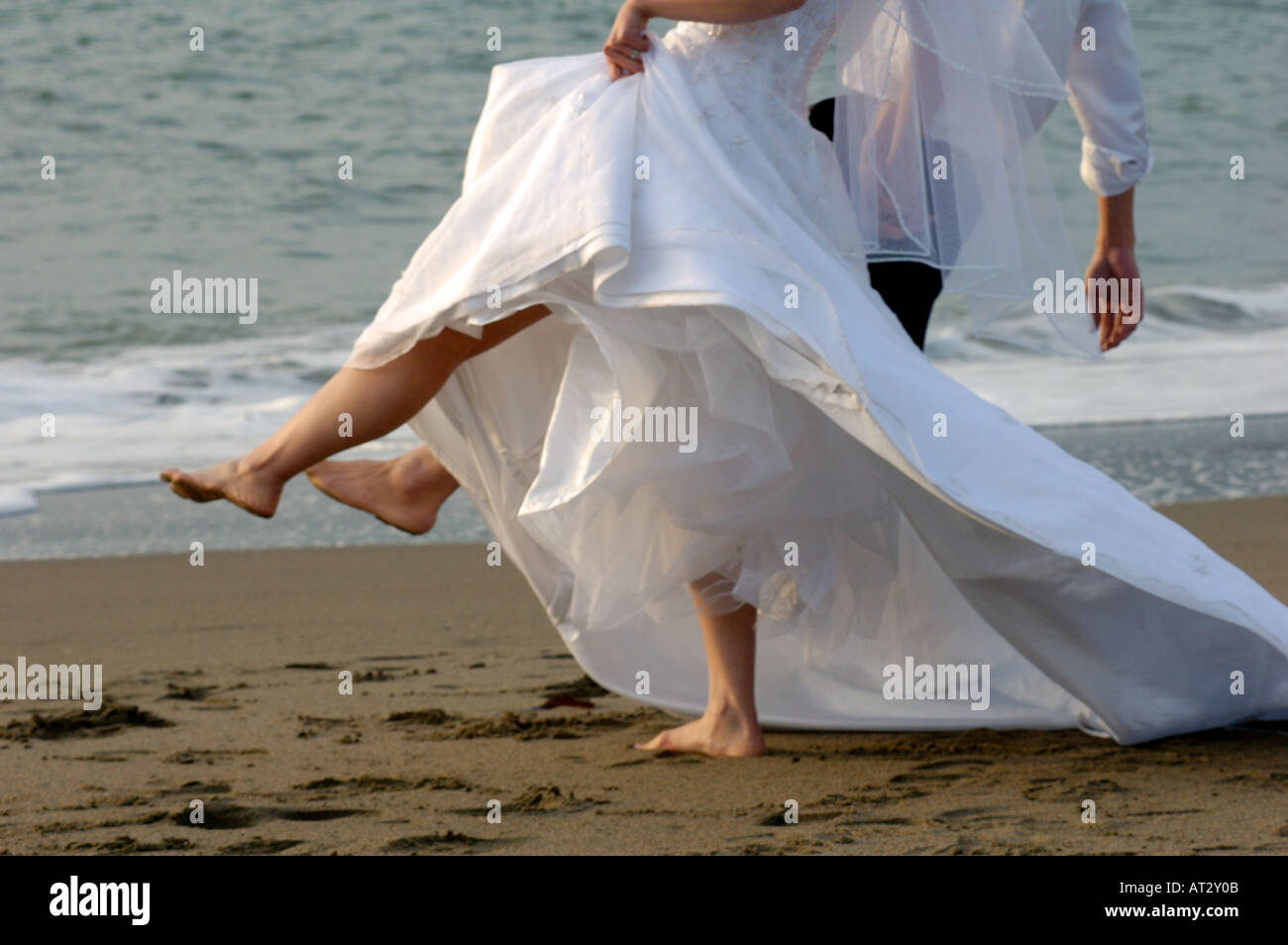 Sposa e lo Sposo calci gambe fino dalle acque dell'oceano di bordo Foto Stock