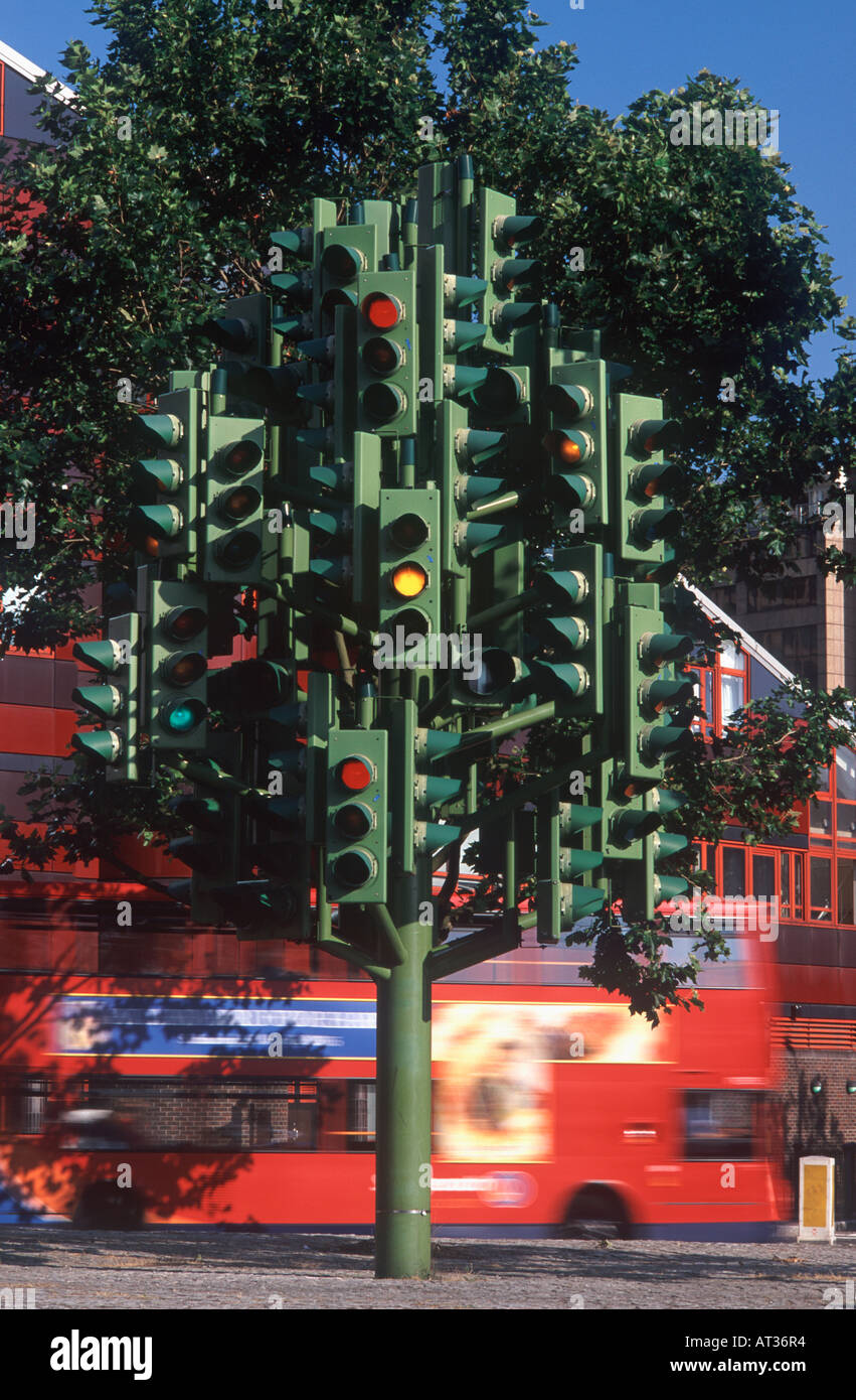 Semaforo tree scultura (Pierre Vivant, 1998) al centro della rotonda con red bus doubledecker dietro, London Docklands Foto Stock