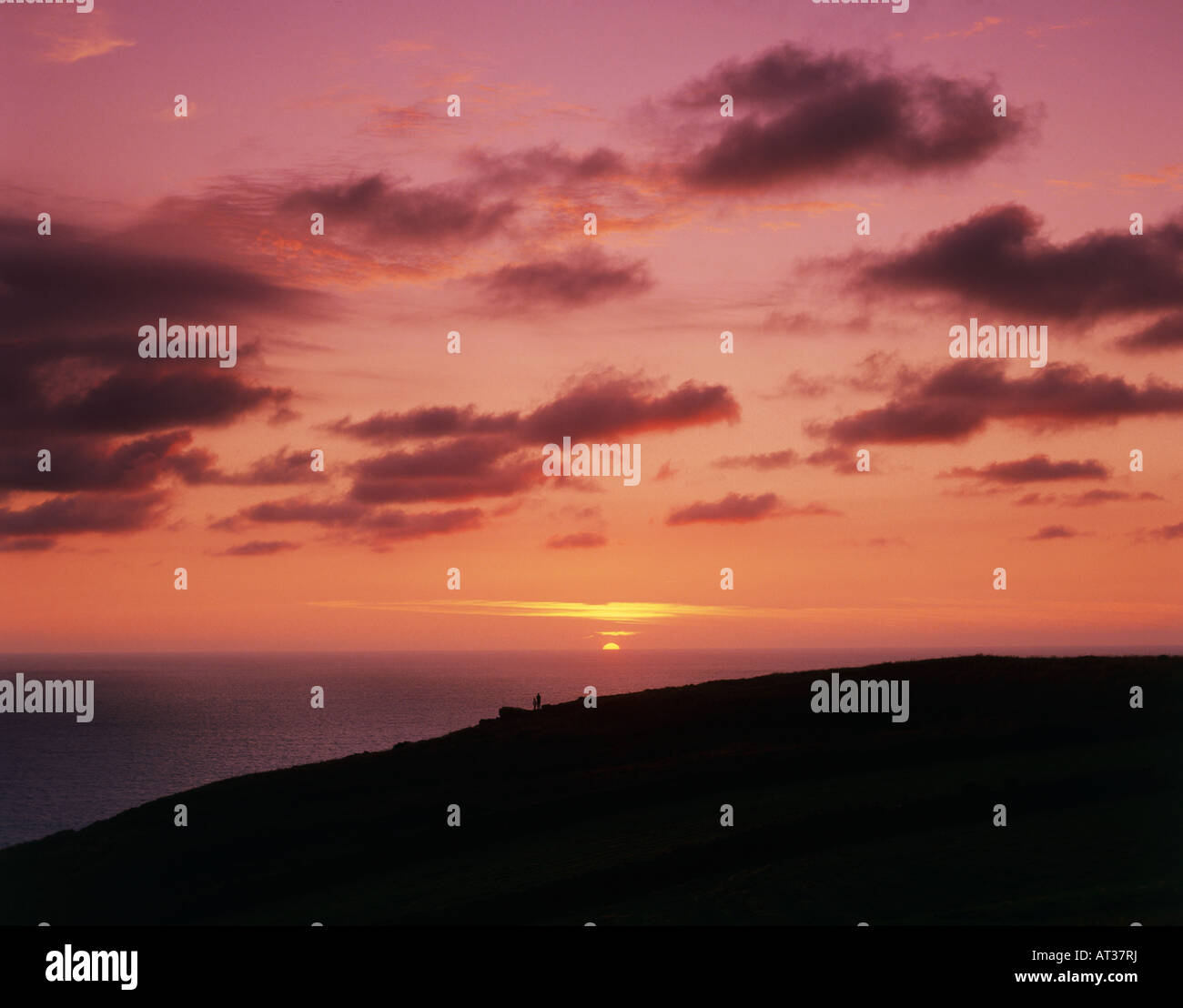 Due persone a guardare il tramonto sul mare Foto Stock