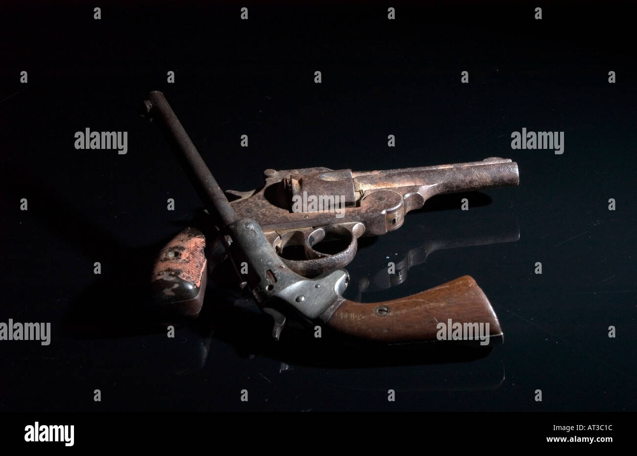Antique 22 calibro pistola di boot e Iver Johnson 32 calibro revolver nero su sfondo riflettente Foto Stock