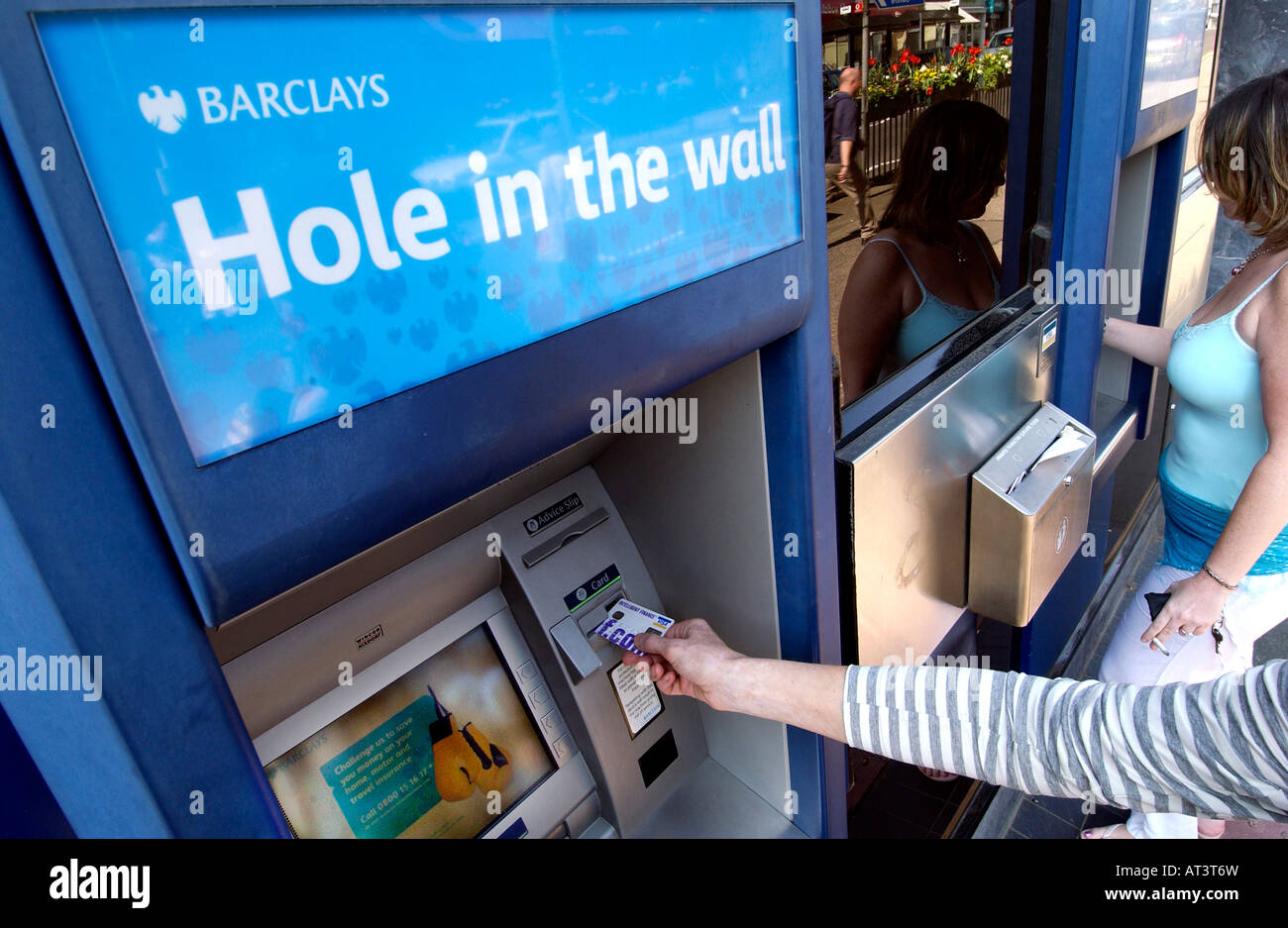 Un Barclays Bank foro nella parete bancomat con qualcuno in possesso di una carta di credito Foto Stock