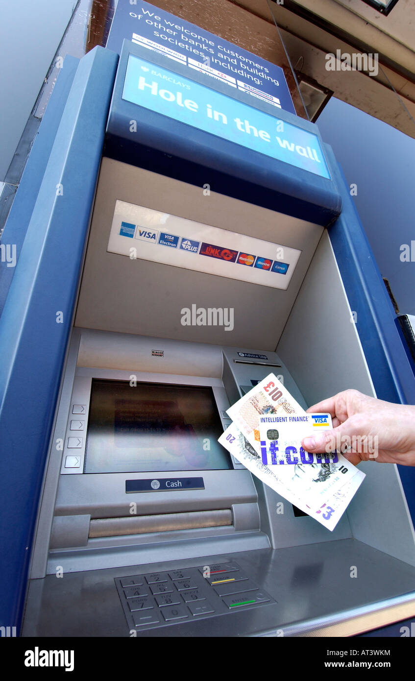 Un Barclays Bank foro nella parete bancomat con qualcuno in possesso di una carta di credito e contanti Foto Stock